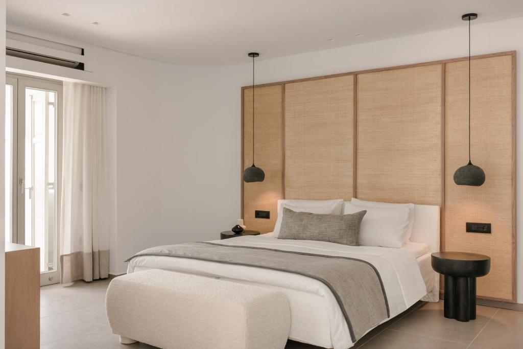 a bedroom with a large bed and a chair at Grace Mykonos in Agios Stefanos