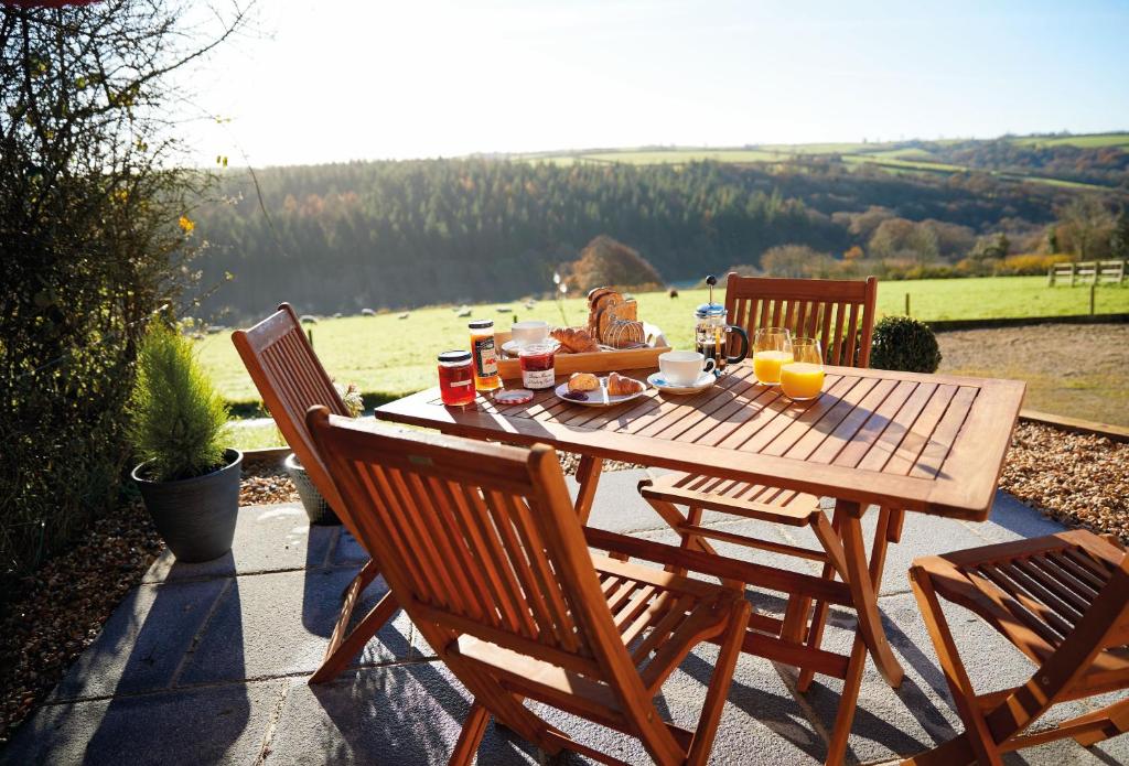 a wooden table with food and drinks on a patio at Seekings Cottage in Knowstone