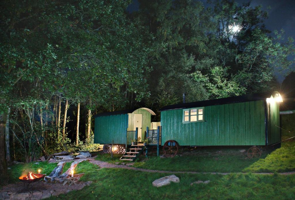 a green shed next to a camp fire at night at Anne's Hut Monmouthshire 