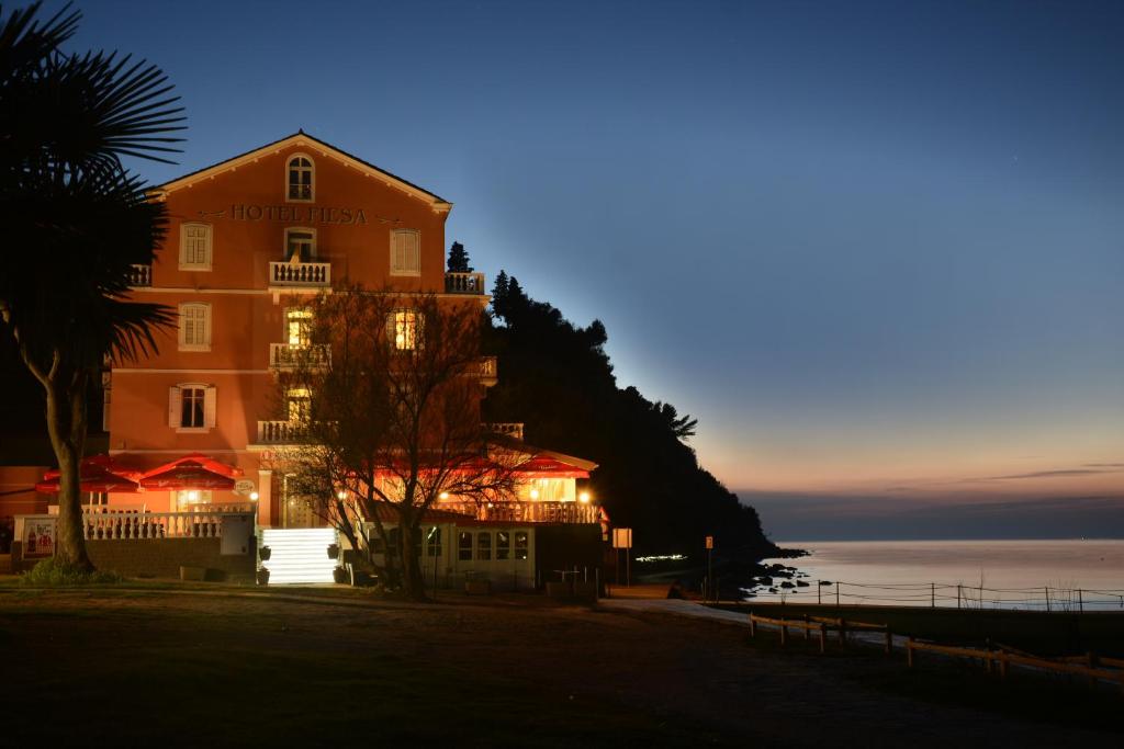 a hotel at night with the ocean in the background at Hotel Fiesa in Piran