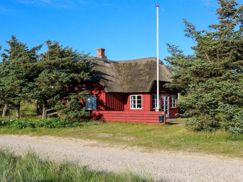 een rood huis met een rieten dak naast een weg bij Holiday Home Jorid - 300m from the sea in Western Jutland by Interhome in Vejers Strand