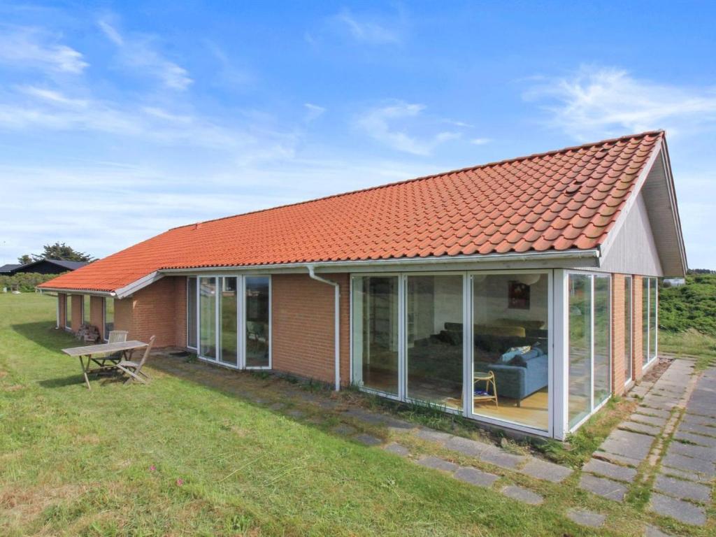 une maison au toit rouge avec portes coulissantes en verre dans l'établissement Holiday Home Amalia - 500m from the sea in NW Jutland by Interhome, à Hjørring