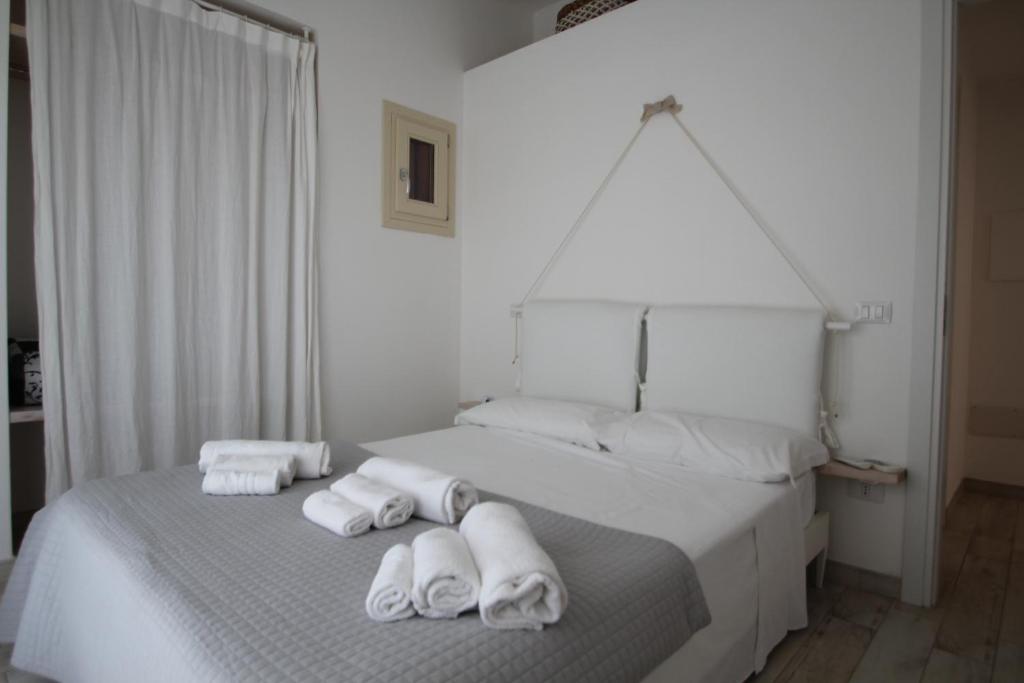 Un dormitorio con una cama blanca con toallas. en VILLA ASFODELO-INFINITYHOLIDAYS, en Costa Paradiso