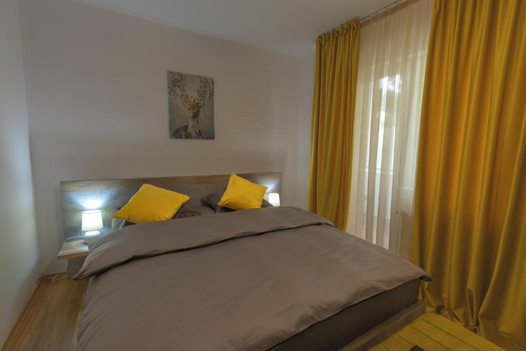 Un dormitorio con una cama con almohadas amarillas y una ventana en Luxury 2 bedroom holiday apartment, en Piteşti
