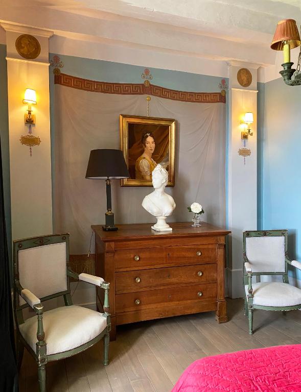 una camera da letto con un comò con un dipinto e due sedie di Manoir de Ghaisne a Freigné