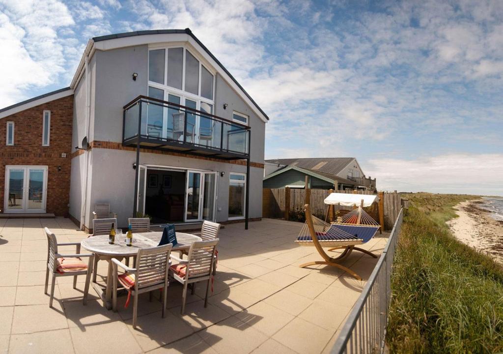 a house with a patio with a table and chairs at Beadnell Beach House in Beadnell