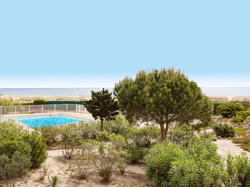 Elle offre une vue sur un jardin avec une piscine et des arbres. dans l&#39;établissement Apartment Mykonos-3 by Interhome, à Port-Leucate
