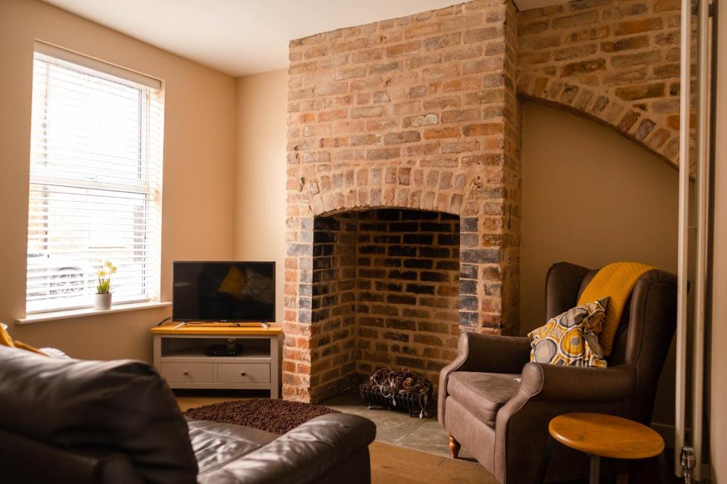 a living room with a brick fireplace with two chairs at Rose Cottage in Shrewsbury