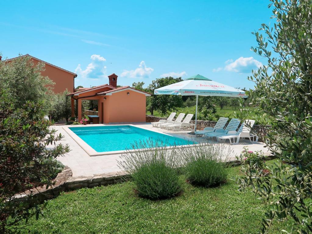 - une piscine avec un parasol et deux chaises dans l'établissement Apartment Rosa - LBN380 by Interhome, à Krnica