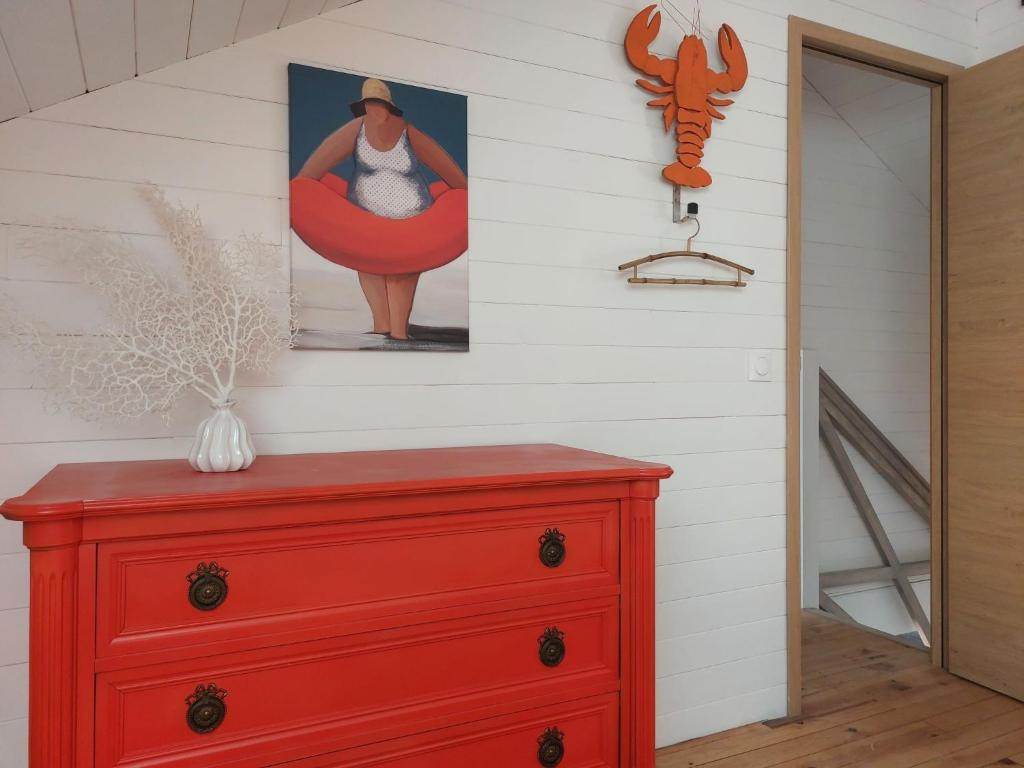 a red dresser in a room with a painting on the wall at Holiday Home Saint-Colomban-2 by Interhome in Carnac