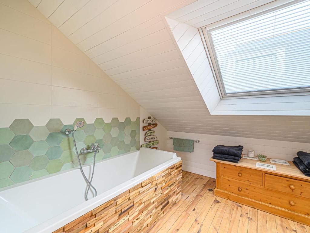 a attic bathroom with a bath tub and a window at Holiday Home Saint-Colomban-2 by Interhome in Carnac