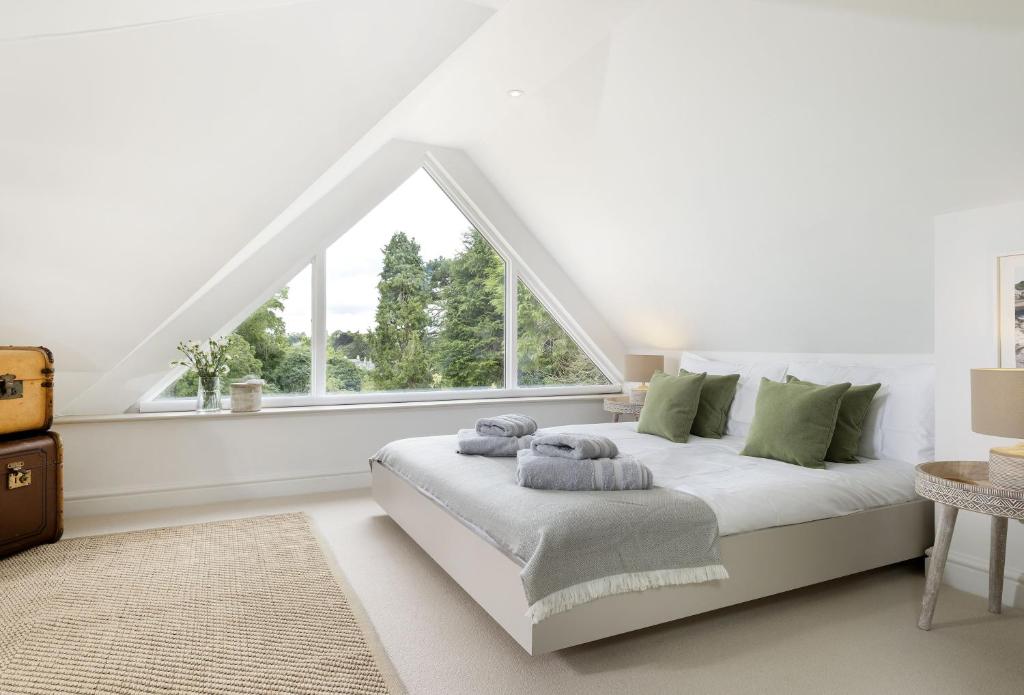 a white bedroom with a bed and a window at Winacres Cottage in Nailsworth