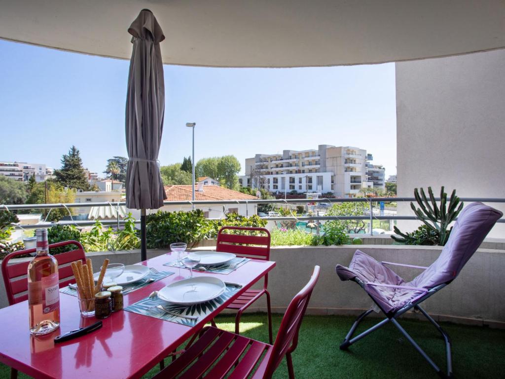 d'une table et de chaises rouges sur un balcon. dans l'établissement Apartment Le Lagon Bleu by Interhome, à Cagnes-sur-Mer