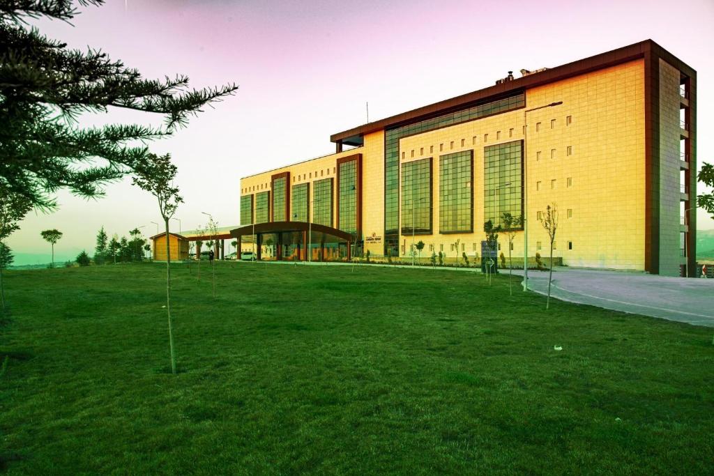 um edifício com um campo de relva à sua frente em Lavanta Tepesi Hotel ve Spor Tesisleri em Burdur