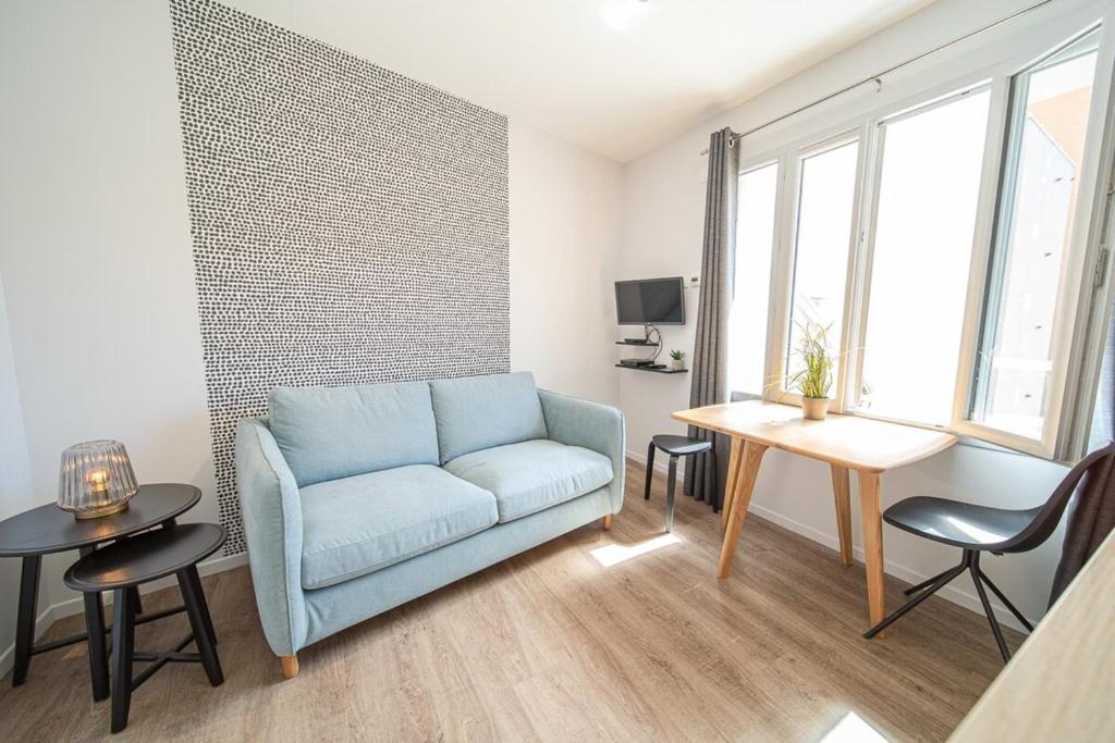 een woonkamer met een blauwe bank en een tafel bij Appartement Lumière- Oullins centre-Lyon in Oullins