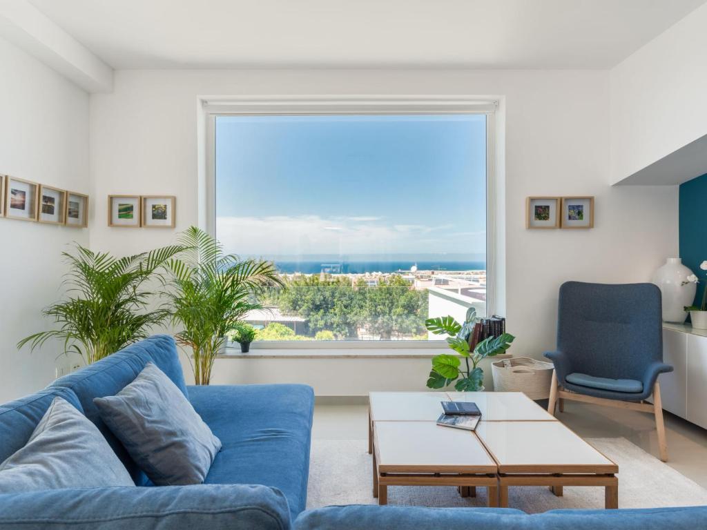 een woonkamer met een blauwe bank en een groot raam bij Apartment Quirat Superior by Interhome in Terrasini