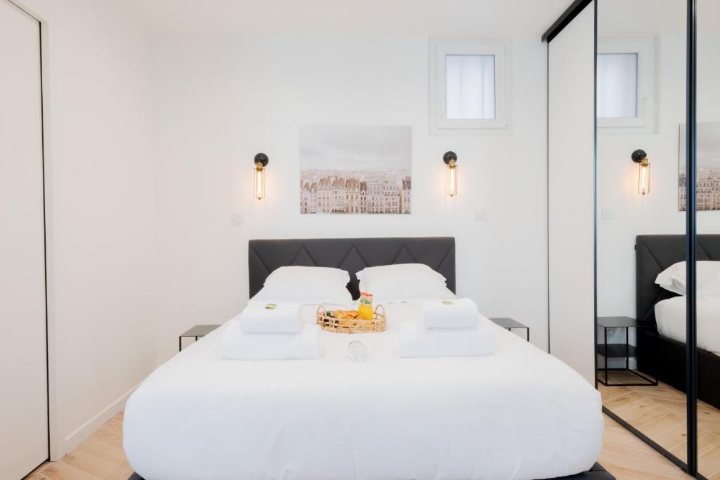 une chambre avec un grand lit blanc et un miroir dans l'établissement Appartement confortable 1BR-4P - Boulogne-Billancourt, à Boulogne-Billancourt