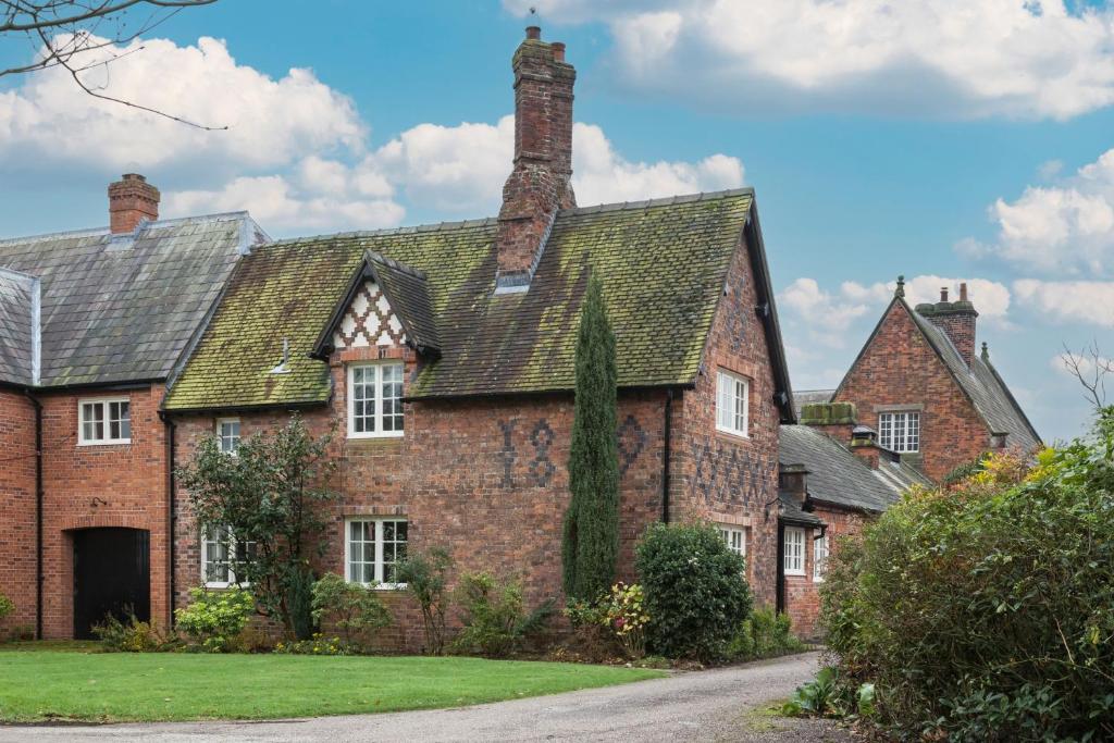 an old red brick house with a green yard at Laundry Cottage in Pickmere