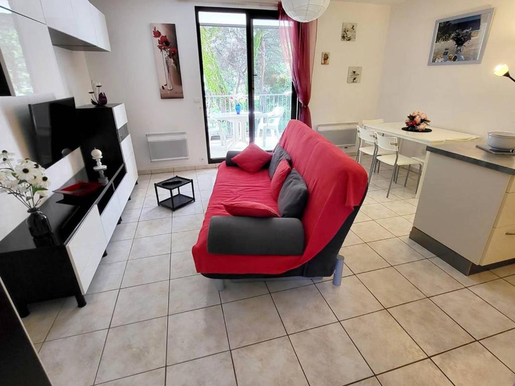 un salon avec un canapé rouge et une cuisine dans l'établissement Appartement T2 avec piscine, tennis et parking - À 400 m des plages et commerces - FR-1-316-16, à Six-Fours-les-Plages
