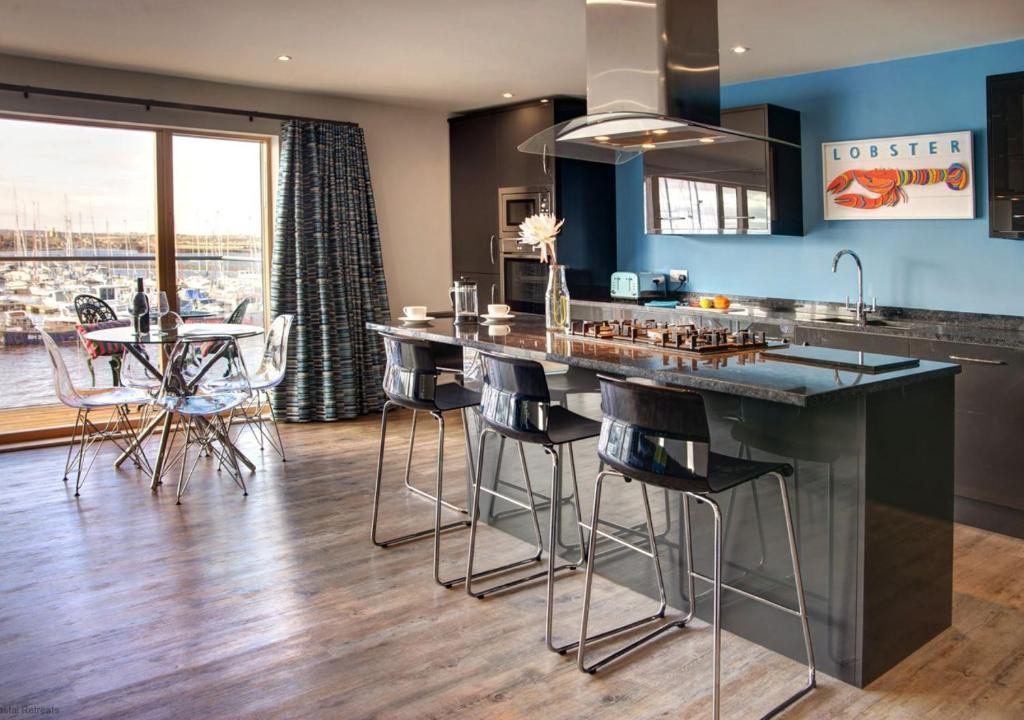 a kitchen with a large island with bar stools at Quayside in Amble