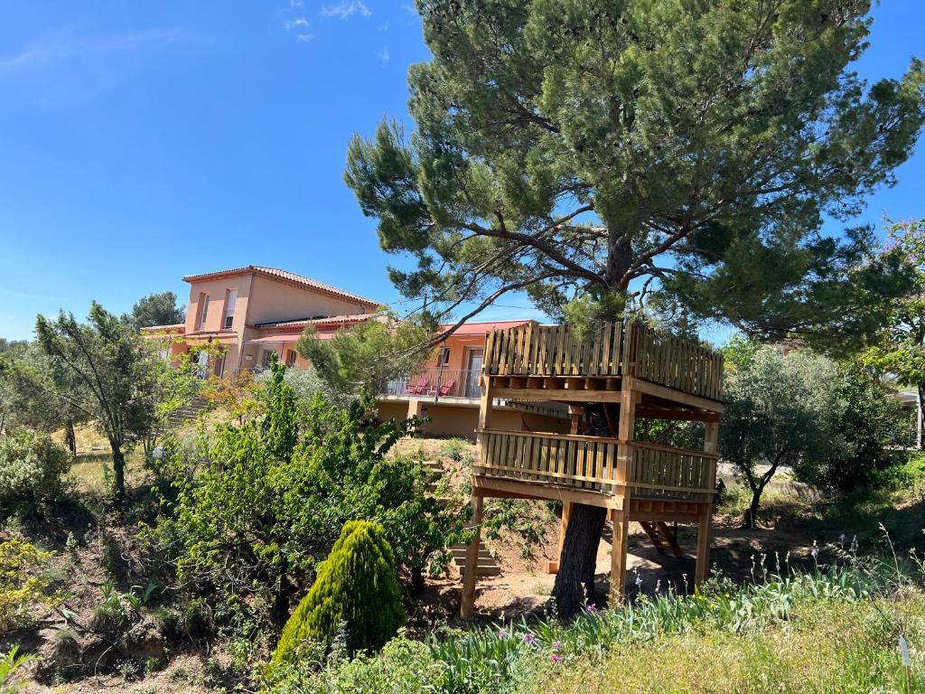 uma casa na árvore em frente a uma casa em DOMAINE MAXXIM em Clermont-lʼHérault