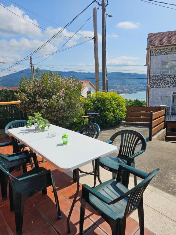 einen weißen Tisch und Stühle auf einer Terrasse in der Unterkunft Casa vistas a la ría in Moaña