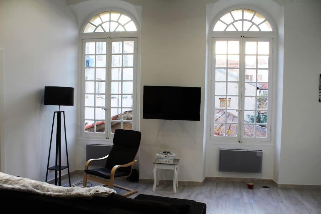 a living room with two windows and a tv at appartement Menton au coeur de la vieille ville in Menton