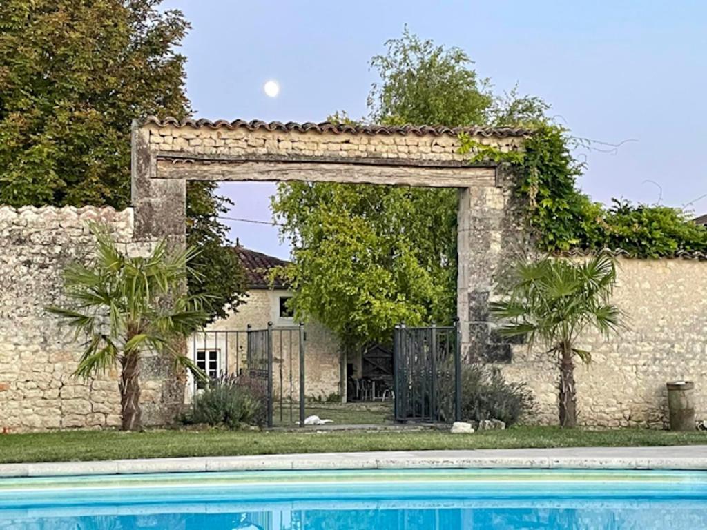 un edificio in pietra con arco sopra la piscina di Maison de 3 chambres avec jardin clos et wifi a Saint Palais du Ne 