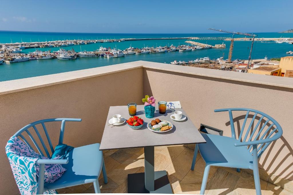 a table with food on a balcony with a view of a harbor at RoccaRegina Hotel in Sciacca