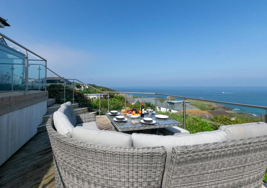 a balcony with wicker chairs and a table and the ocean at Carthew House Carthew Way in St Ives