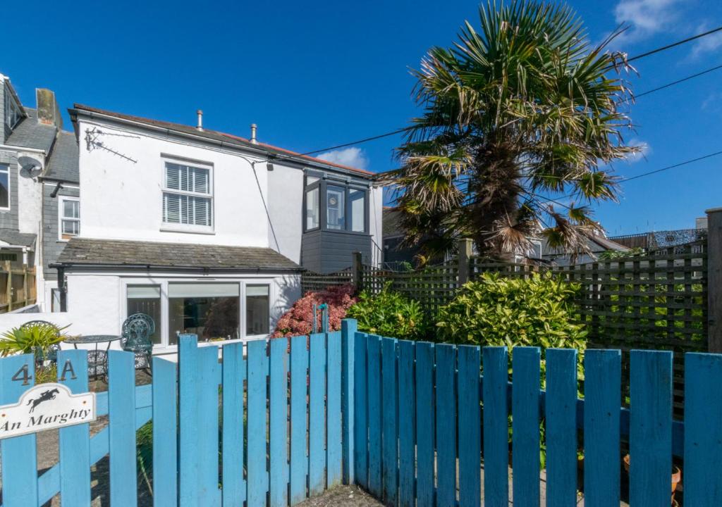 a blue fence in front of a house with a palm tree at An Marghty 4a Carthew Terrace in St Ives