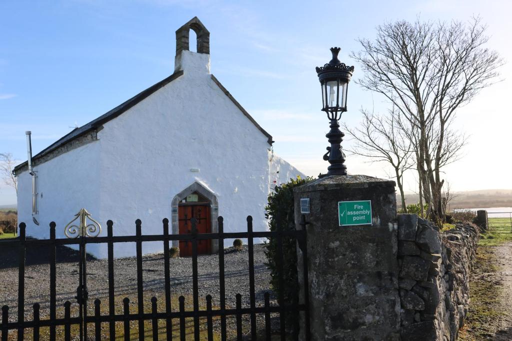 uma igreja com uma luz de rua em frente a uma cerca em The Burren Art Gallery built in 1798 em Tubber