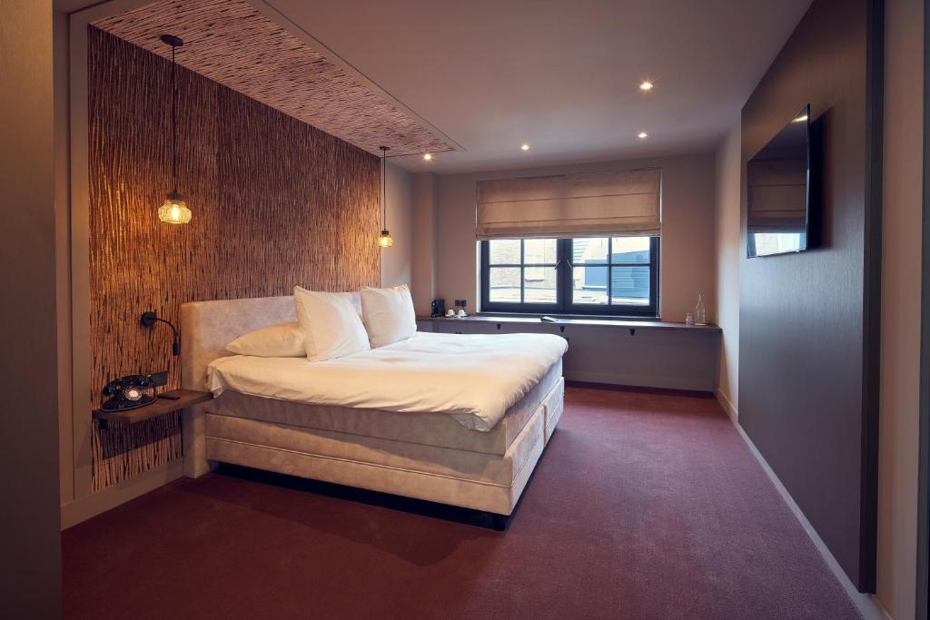 - une chambre avec un grand lit et une fenêtre dans l'établissement The Yard hotel Noordkade, à Veghel