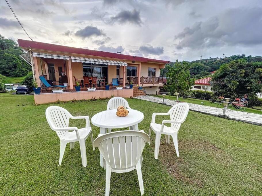 uma mesa branca e cadeiras num quintal com uma casa em Villa Les 12 Zicaques em Saint-Joseph