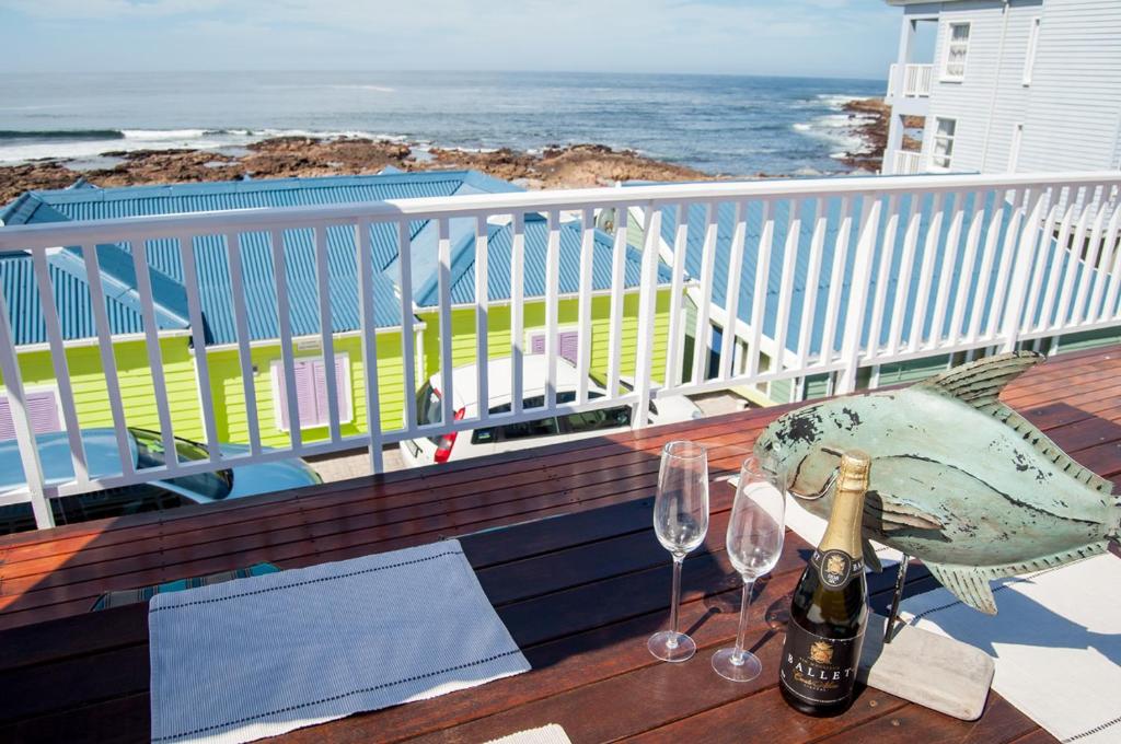 einen Tisch mit zwei Weingläsern und einem Fisch auf dem Balkon in der Unterkunft Barefoot Lodge, Mossel Bay in Mossel Bay