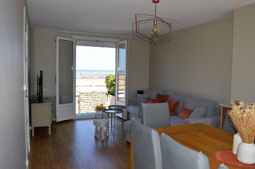 a living room with a table and a couch at L'Estran - maison sur la digue avec vue mer in Courseulles-sur-Mer