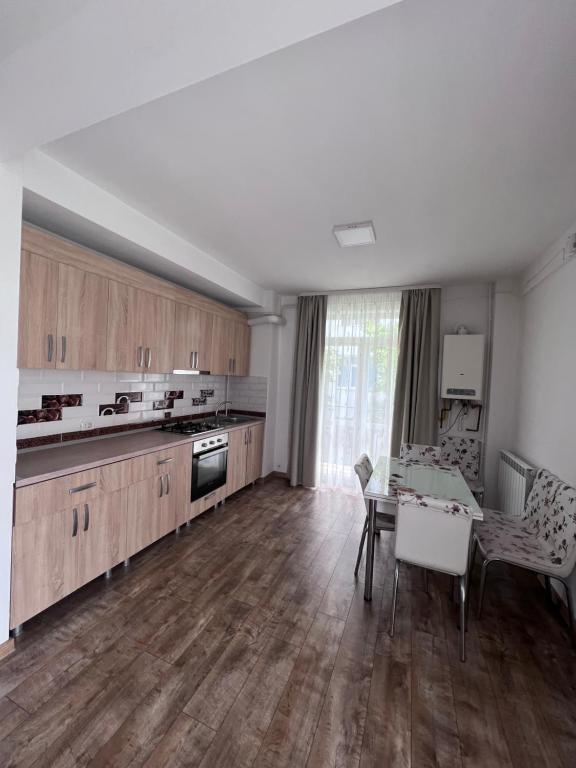 a kitchen with wooden cabinets and a table and a dining room at Nesta Apartament in Fălticeni