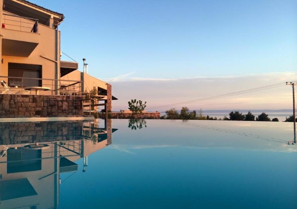 a swimming pool in front of a house with blue water at Olivia Estate Villa with Private Swimming Pool in Elia