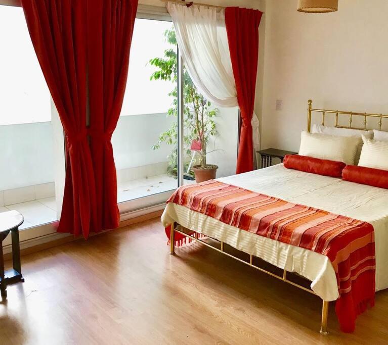 1 dormitorio con 1 cama con cortinas rojas y ventana en HART - STUDIO MELO en Buenos Aires