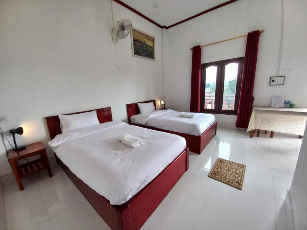 a bedroom with two beds and a sink in it at Sipanya Guesthouse in Muang Phônsavan