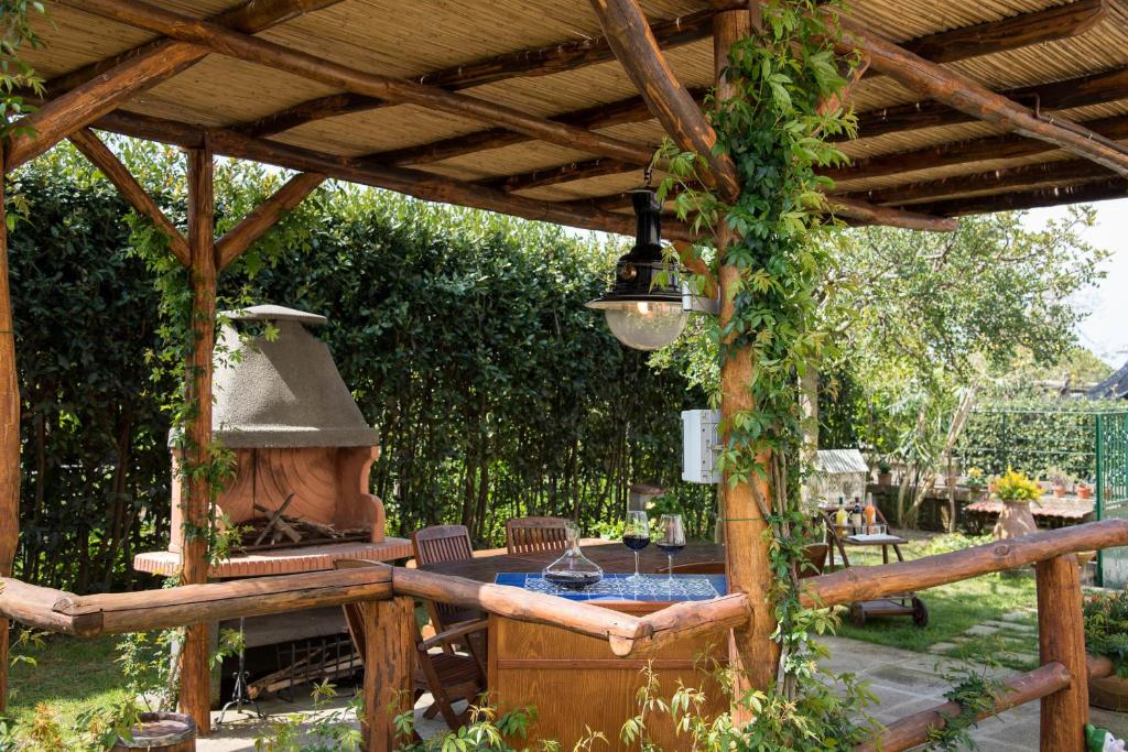 a wooden pergola with a table and an outdoor oven at B&B La Casa Nel Giardino in Piano di Sorrento