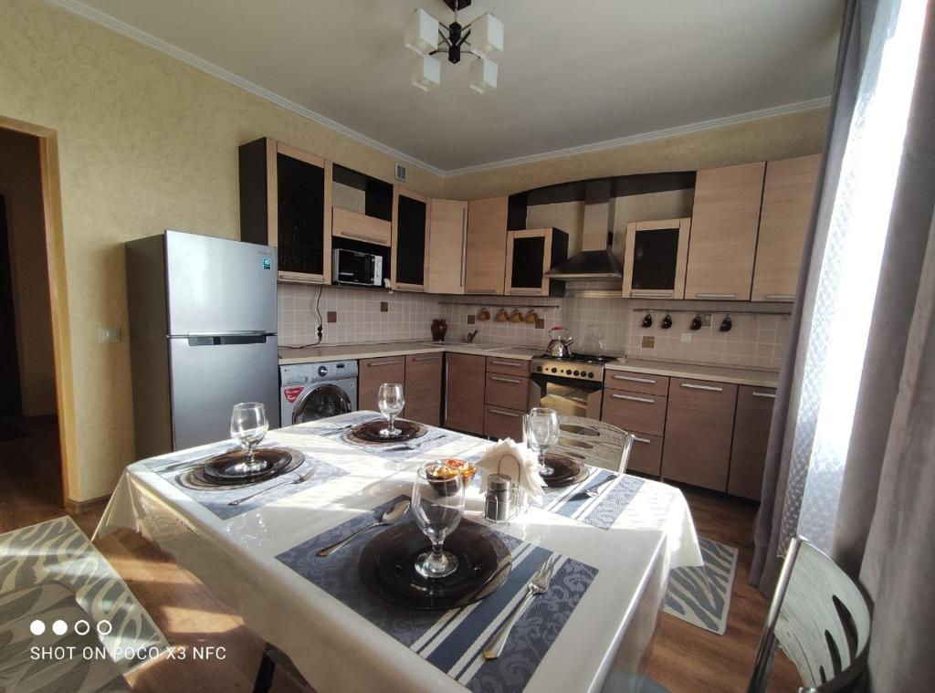 a kitchen with a table and a refrigerator at Уютная однокомнатная квартирка, в тихом спальном районе, недалеко от Аэропорта in Almaty