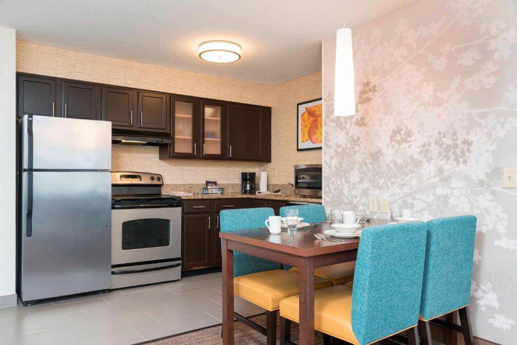 a kitchen with a table and a refrigerator at Residence Inn by Marriott Grand Rapids West in Grand Rapids