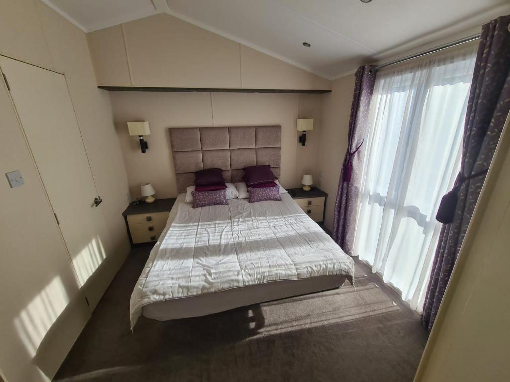 a bedroom with a bed with purple pillows and a window at Rockley Park, Gorse Hill 39 in Lytchett Minster