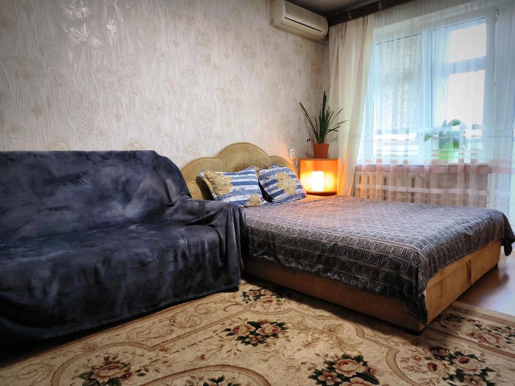 a bedroom with a couch and a bed and a window at Уютная квартира возле ТЦ Вавилон, Ж/м Солнечный, Малиновского 12, 1-к in Dnipro
