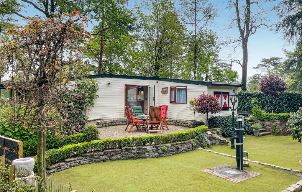 um pequeno chalé branco com uma mesa e cadeiras num quintal em Amazing Home In Beekbergen With Outdoor Swimming Pool, Wifi And 2 Bedrooms em Beekbergen