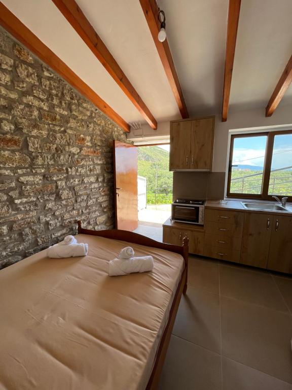 1 dormitorio con cama y pared de piedra en KAFUL APARTMENTS en Qeparo
