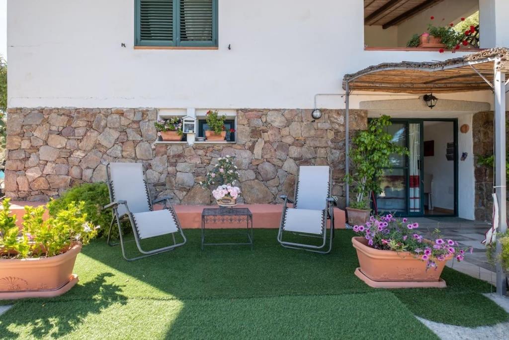 un patio con 3 sillas, una mesa y algunas plantas en [Mare a 4 minuti Auto]Casa/Giardino e WiFi Budoni en Budoni