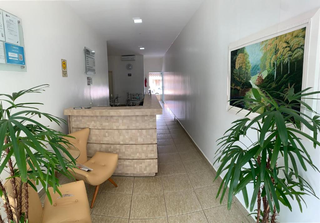 a lobby with two potted plants and a counter at Pissin Plaza Hotel in Goiânia