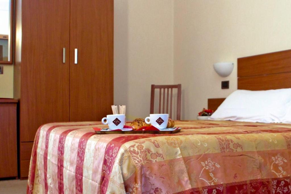 Un dormitorio con una cama con dos tazas. en Hotel Residence Vigone, en Vigone